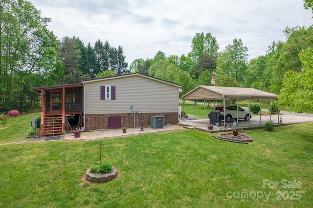rear view of property with a lawn, a carport, cooling unit, and stairs