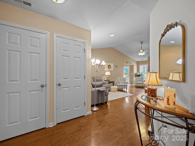 entryway with a ceiling fan, baseboards, wood finished floors, vaulted ceiling, and visible vents