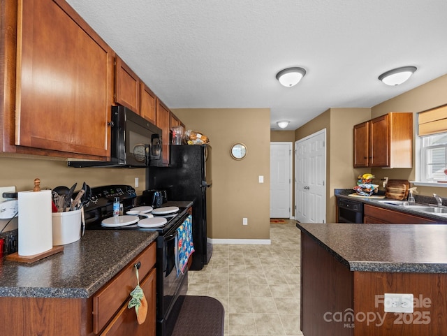 kitchen with a sink, dark countertops, black appliances, and brown cabinets