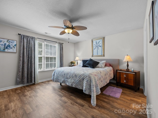 bedroom with visible vents, a ceiling fan, baseboards, and wood finished floors