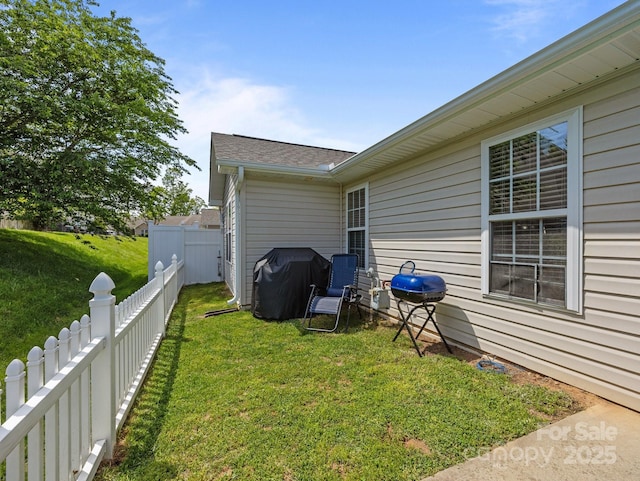 exterior space featuring a fenced backyard, a yard, and a shingled roof