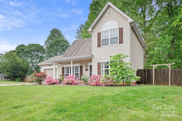 traditional-style house with a front lawn, an attached garage, and fence