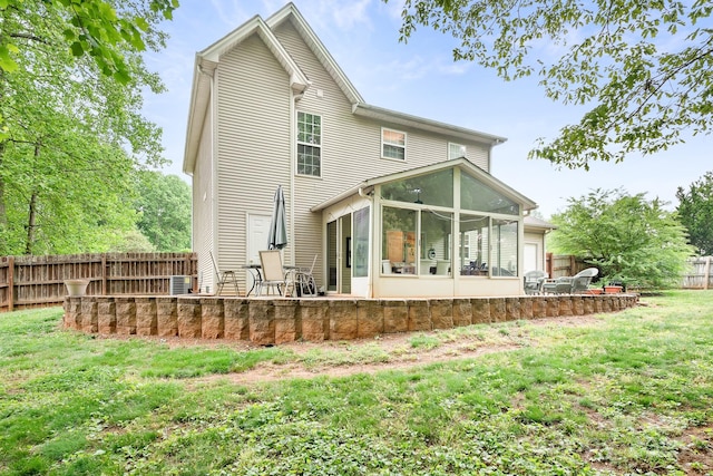 back of house featuring a sunroom, a yard, a fenced backyard, and a patio area