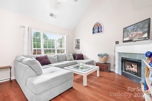 living room with visible vents, a tile fireplace, wood finished floors, a ceiling fan, and high vaulted ceiling