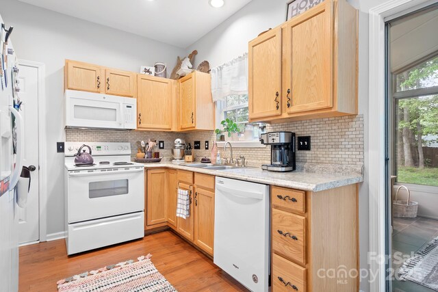 kitchen featuring white appliances, light brown cabinets, light wood-style flooring, light countertops, and a sink