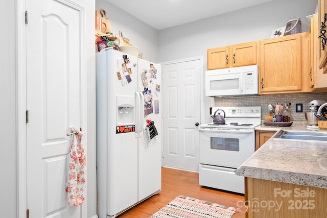 kitchen with white appliances, light brown cabinets, light countertops, a sink, and light wood-type flooring