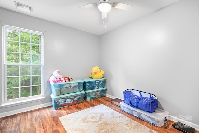 playroom featuring wood finished floors, visible vents, ceiling fan, and baseboards