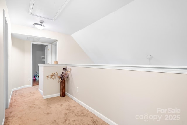 corridor with lofted ceiling, visible vents, baseboards, attic access, and carpet