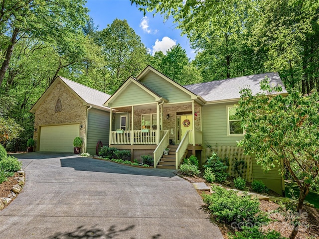 ranch-style home featuring covered porch, asphalt driveway, brick siding, and an attached garage