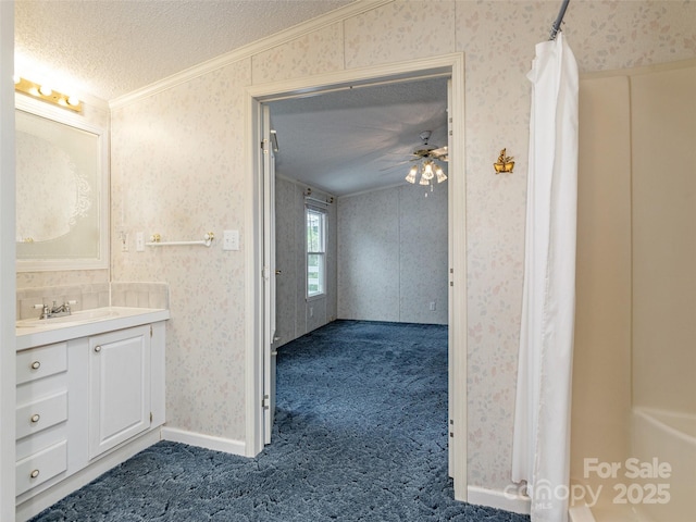 full bath featuring a textured ceiling, vanity, ornamental molding, and wallpapered walls