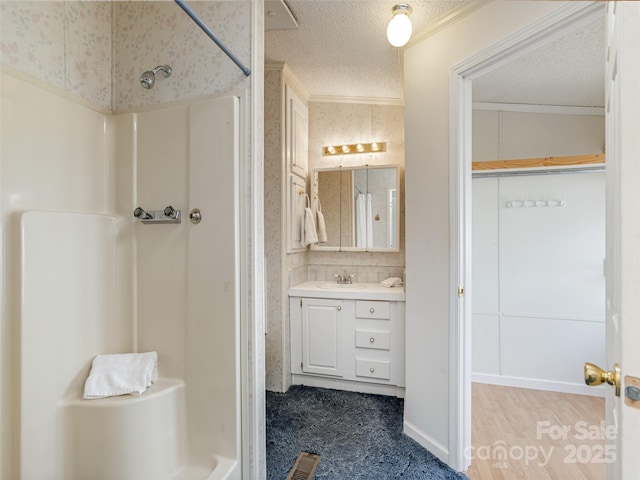 full bathroom featuring walk in shower, vanity, visible vents, a textured ceiling, and crown molding