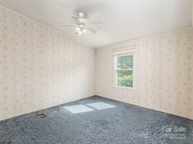carpeted spare room featuring a textured ceiling, a ceiling fan, ornamental molding, and wallpapered walls