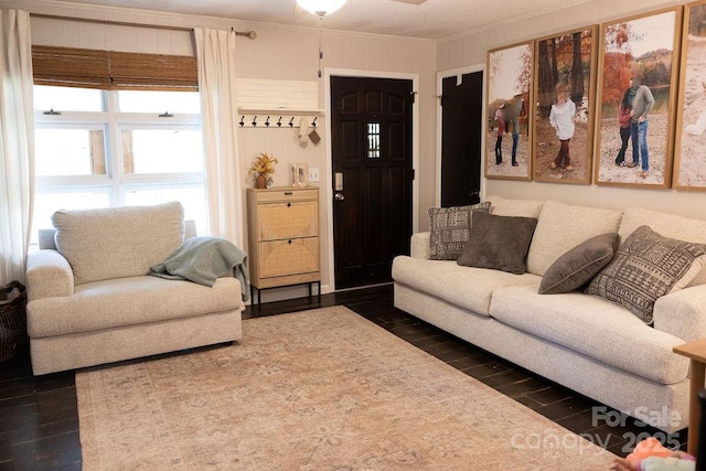 living area with crown molding, a ceiling fan, and dark wood-style floors