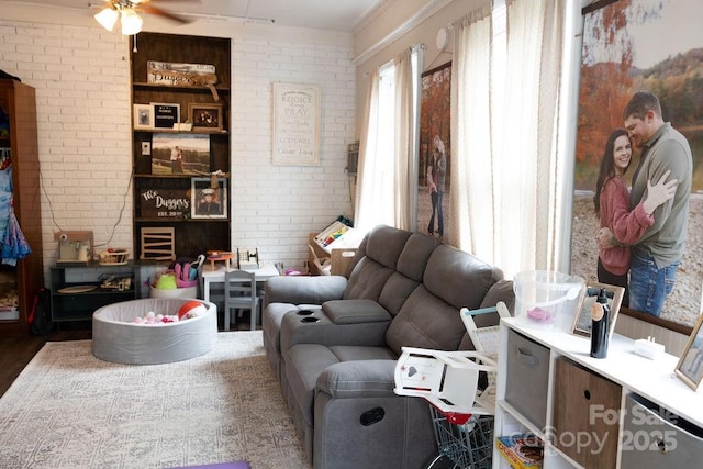 living area featuring a ceiling fan, wood finished floors, and brick wall