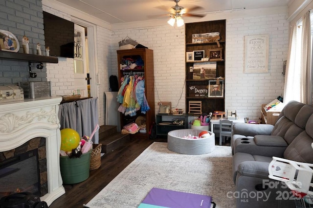 living area with crown molding, brick wall, ceiling fan, and dark wood-type flooring