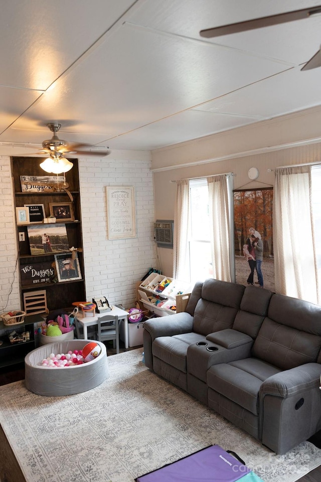 living area featuring ceiling fan, a wealth of natural light, and brick wall