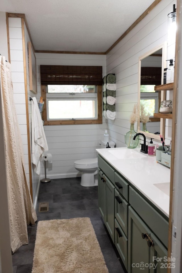 bathroom with wooden walls, a sink, toilet, double vanity, and a shower with shower curtain
