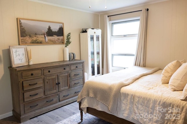 bedroom with ornamental molding and wood finished floors