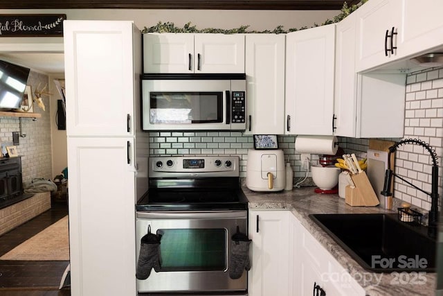 kitchen featuring a sink, white cabinetry, appliances with stainless steel finishes, and tasteful backsplash