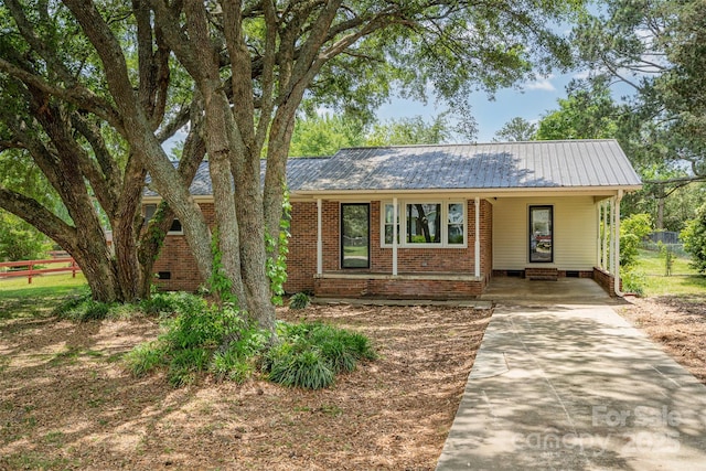 view of front of property with an attached carport, fence, metal roof, concrete driveway, and brick siding