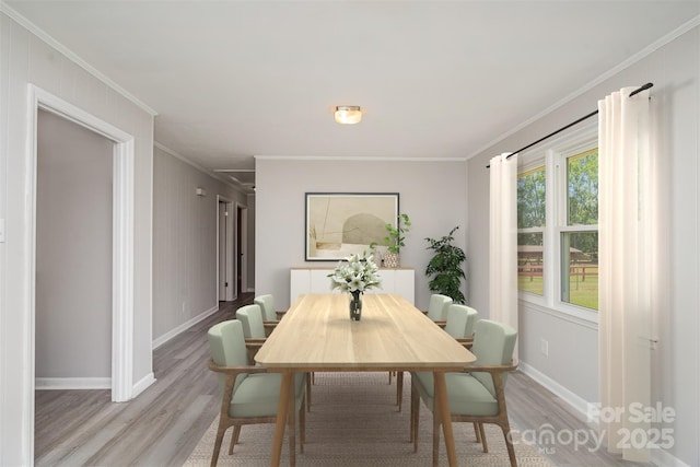 dining space featuring light wood finished floors, crown molding, and baseboards