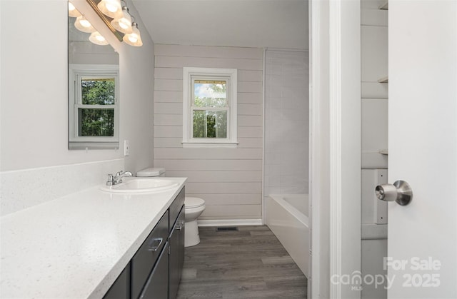 bathroom with toilet, plenty of natural light, wood finished floors, and vanity