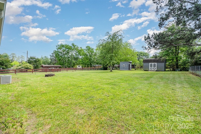 view of yard with a storage shed, an outbuilding, a fenced backyard, and central air condition unit