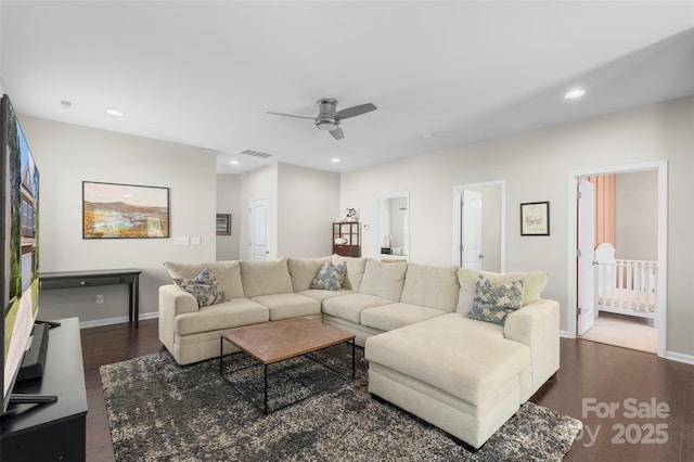 living area with dark wood-style flooring, a ceiling fan, and baseboards