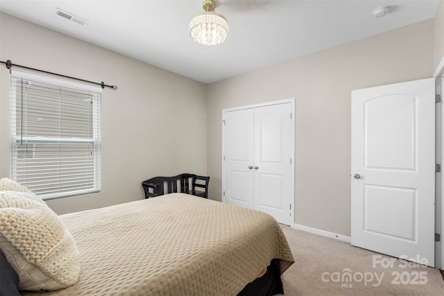 bedroom featuring an inviting chandelier, light carpet, baseboards, visible vents, and a closet