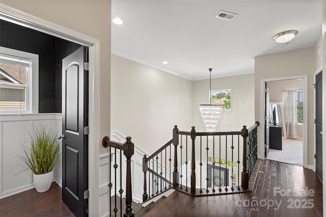 hallway featuring an upstairs landing, wood finished floors, visible vents, and an inviting chandelier