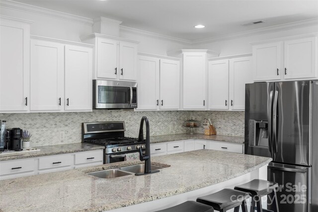 kitchen with a sink, appliances with stainless steel finishes, white cabinets, and a breakfast bar area