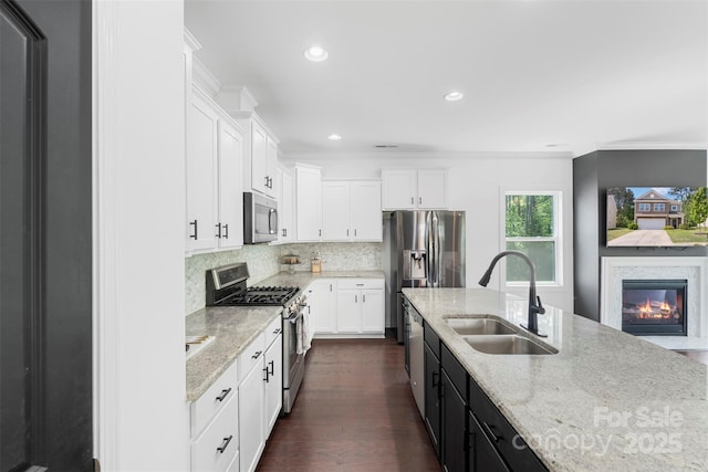 kitchen with light stone counters, a sink, white cabinetry, and stainless steel appliances