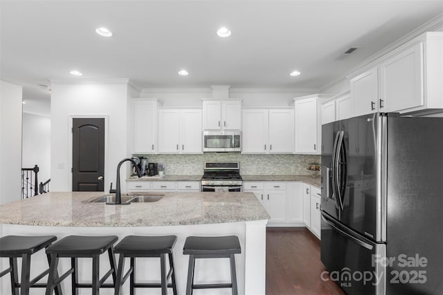 kitchen with a sink, a kitchen breakfast bar, stainless steel appliances, and white cabinetry