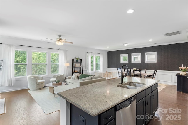 kitchen featuring a sink, dishwasher, a wainscoted wall, open floor plan, and visible vents