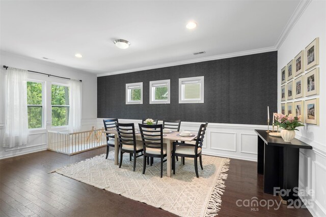 dining room featuring wallpapered walls, visible vents, ornamental molding, and hardwood / wood-style floors