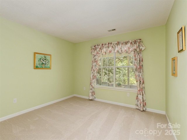 empty room with visible vents, light colored carpet, and baseboards