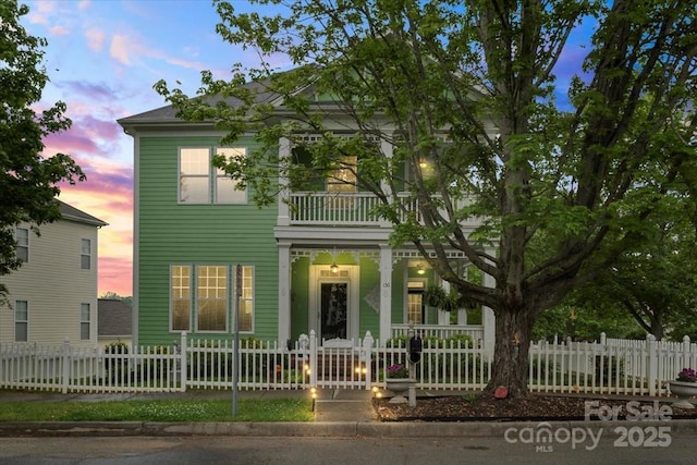 greek revival house with covered porch, a balcony, and a fenced front yard