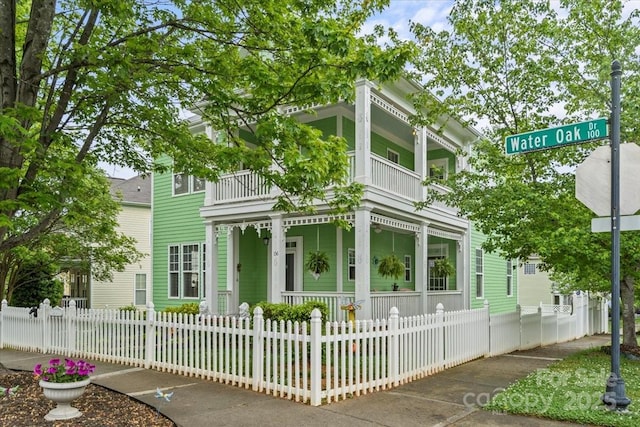 view of front facade featuring covered porch, a balcony, and a fenced front yard