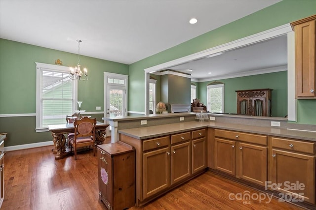 kitchen featuring brown cabinetry, decorative light fixtures, a chandelier, and dark wood-type flooring