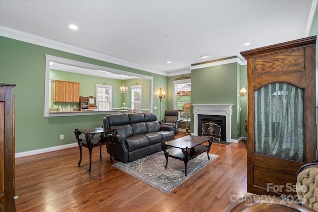 living room with a fireplace with flush hearth, a wealth of natural light, wood finished floors, and crown molding