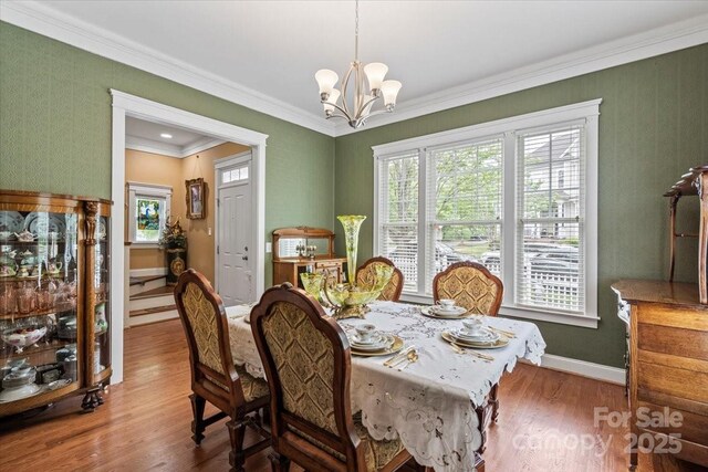 dining space with ornamental molding, a chandelier, wood finished floors, and baseboards