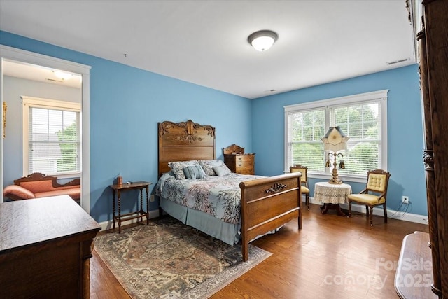 bedroom with wood finished floors, visible vents, and baseboards