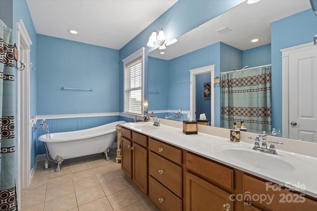 full bathroom featuring double vanity, a freestanding bath, wainscoting, and a sink
