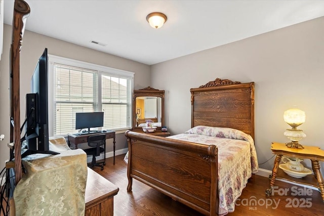 bedroom featuring baseboards, visible vents, and wood finished floors