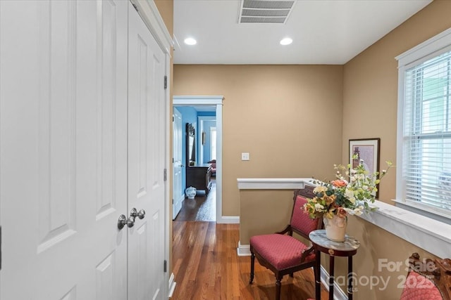 hall featuring wood finished floors, recessed lighting, visible vents, and baseboards