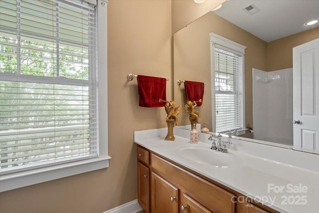 bathroom featuring a healthy amount of sunlight, vanity, visible vents, and baseboards