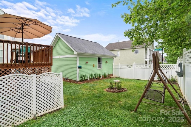view of yard featuring a deck, a fenced backyard, and an outbuilding