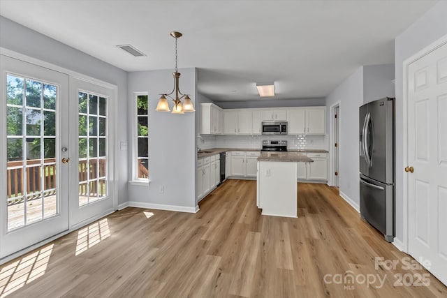 1218 Faversham Ln, Rock Hill, SC 29730 - kitchen featuring stainless steel appliances, a chandelier, white cabinets, light wood-style flooring, and backsplash