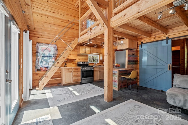 interior space with a sink, wooden ceiling, a barn door, wooden walls, and gas range