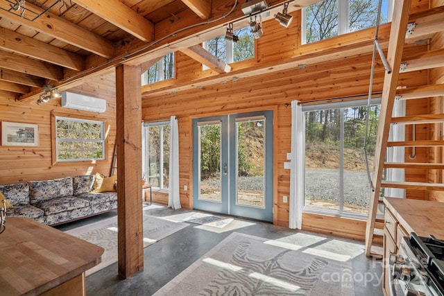 doorway with beamed ceiling, concrete flooring, wood walls, an AC wall unit, and french doors
